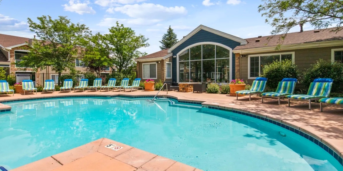 A swimming pool surrounded by lounge chairs and a building in the background.